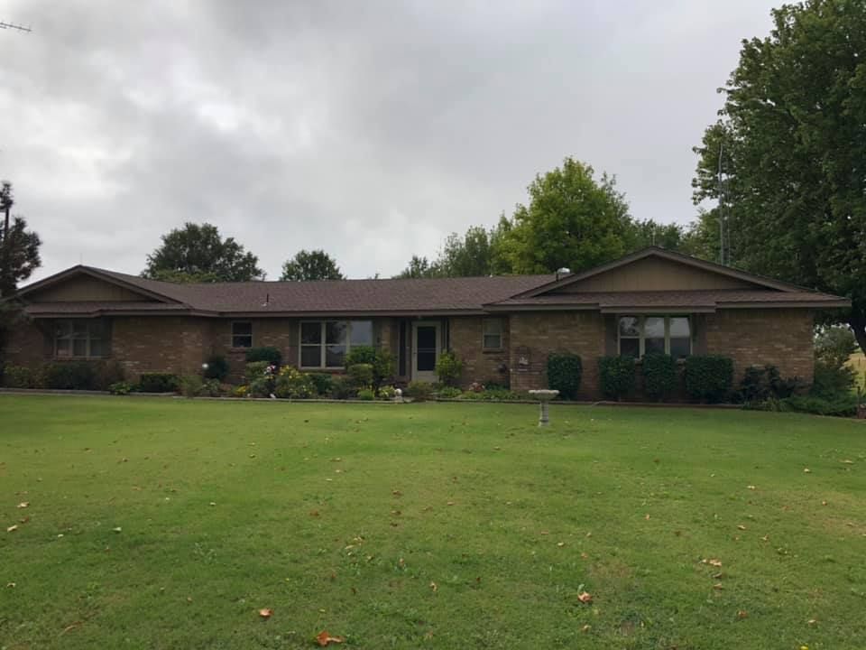 A large brick house with a large lawn in front of it.