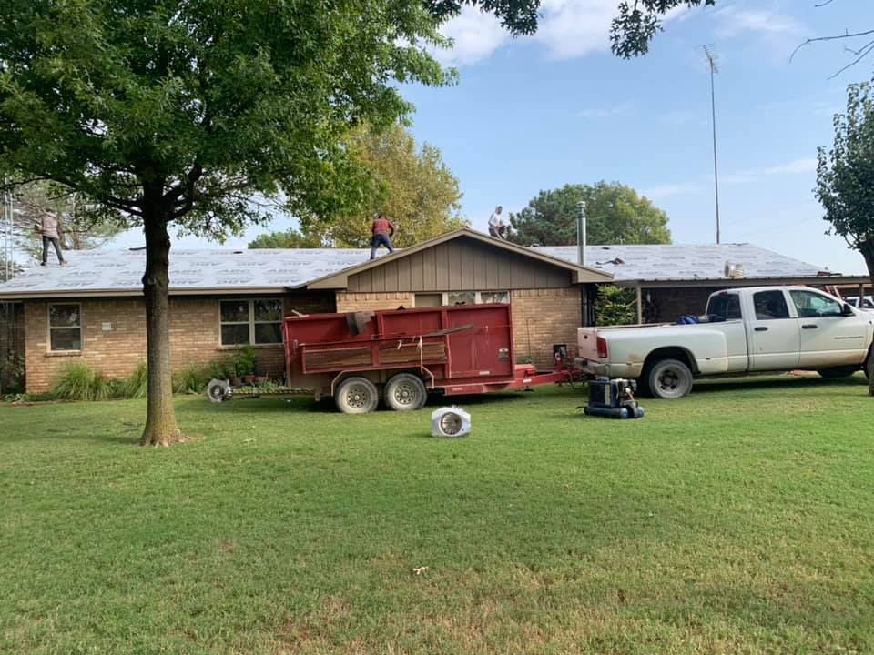 A truck is parked in front of a house with a trailer attached to it.