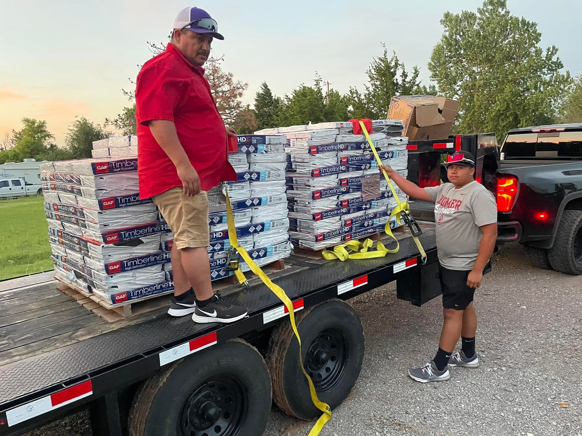 A man and a boy are standing on the back of a trailer.