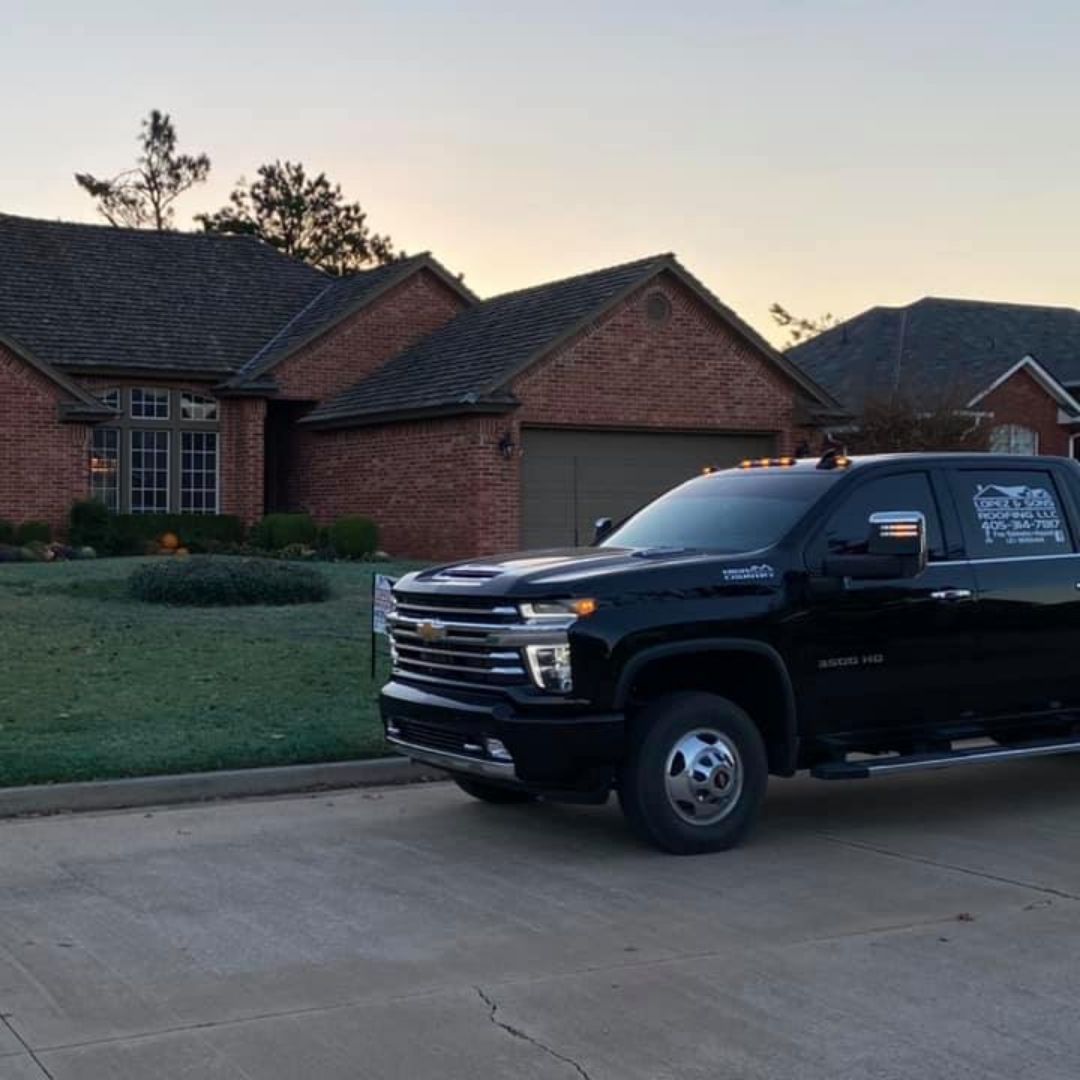 A black truck is parked in front of a brick house