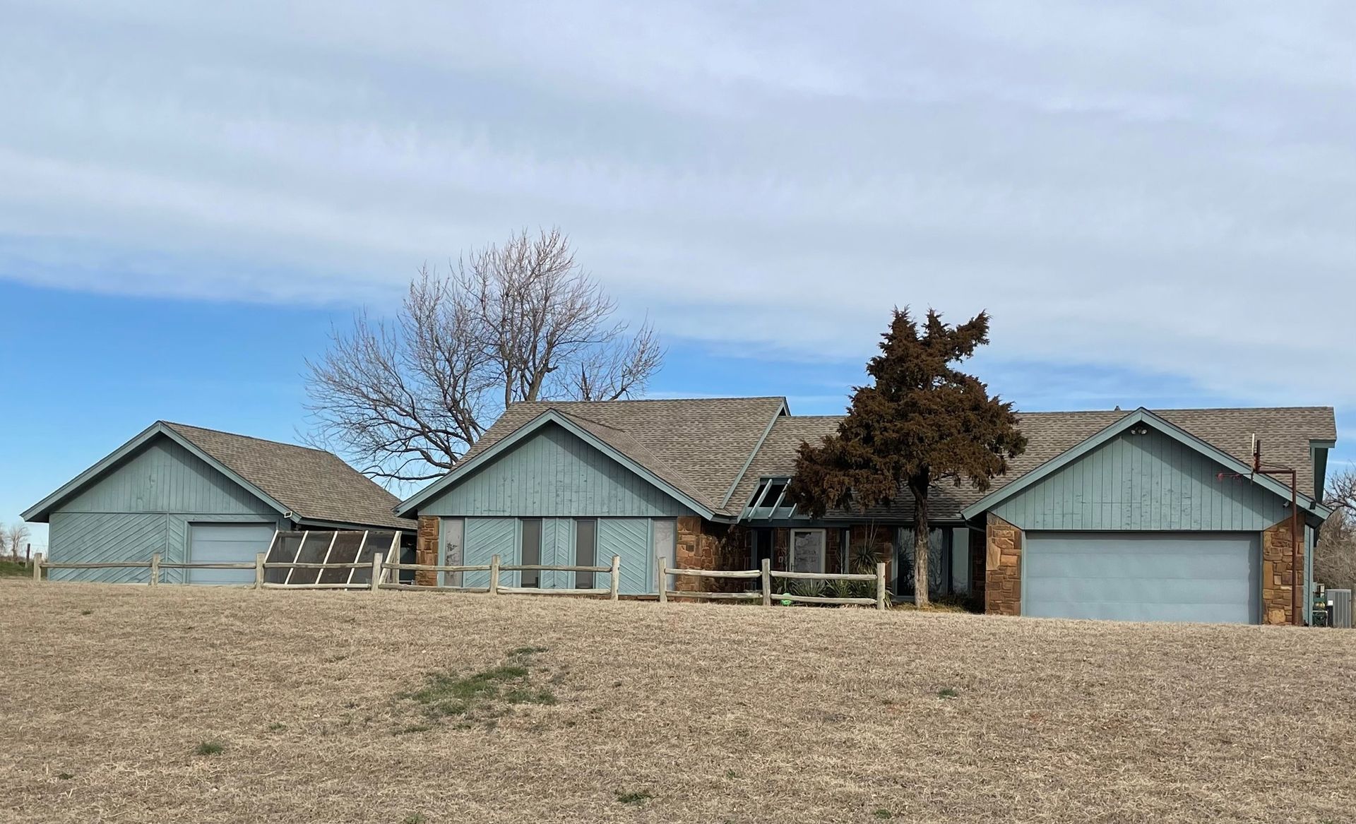 A large house with a lot of garages is sitting on top of a dirt hill.