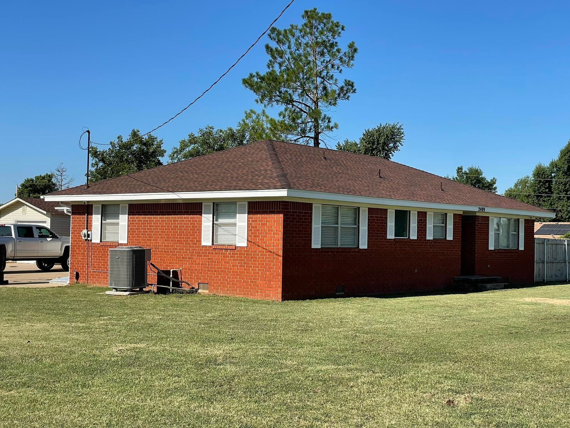 A brick house with a brown roof and white shutters