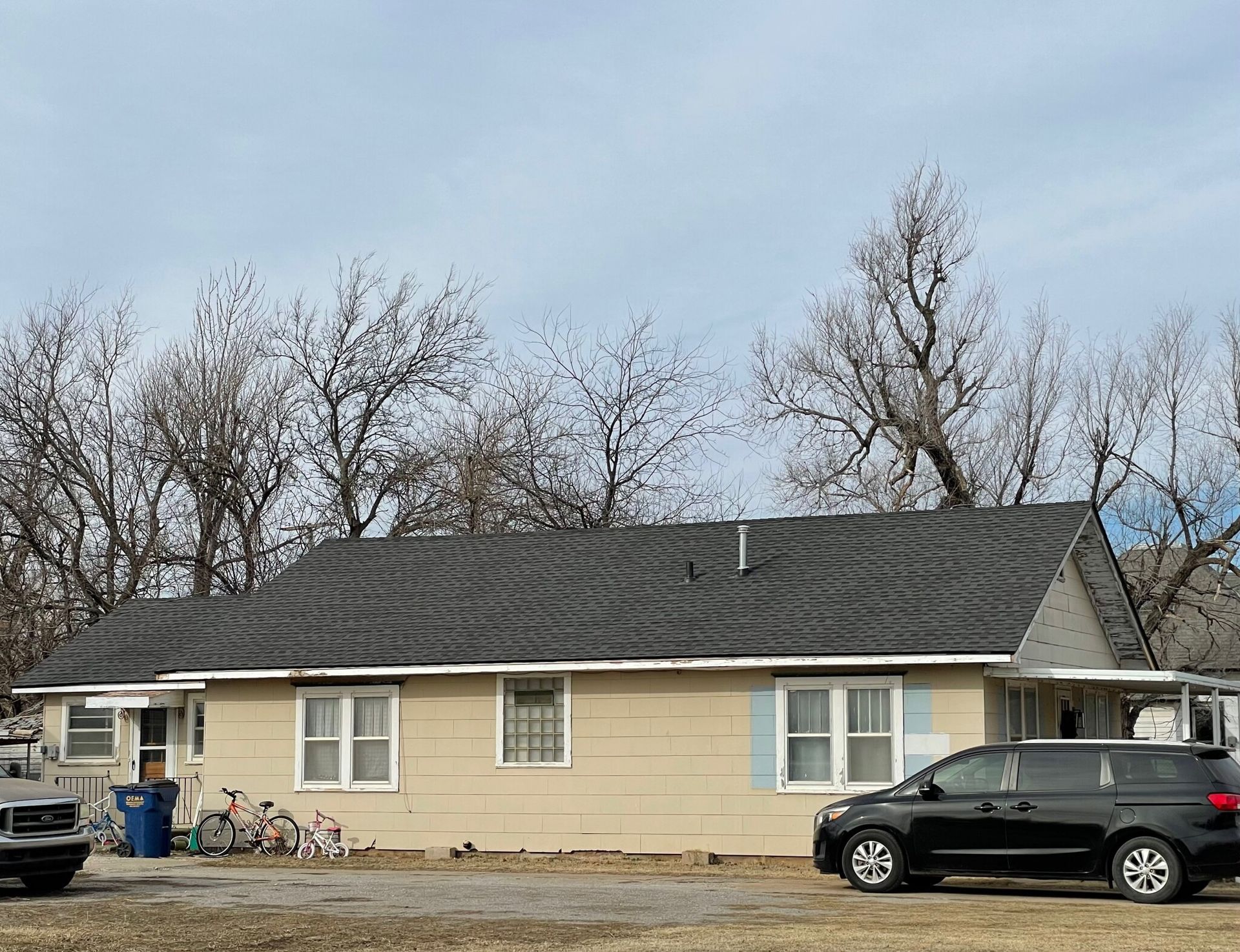 A small house with a black van parked in front of it.