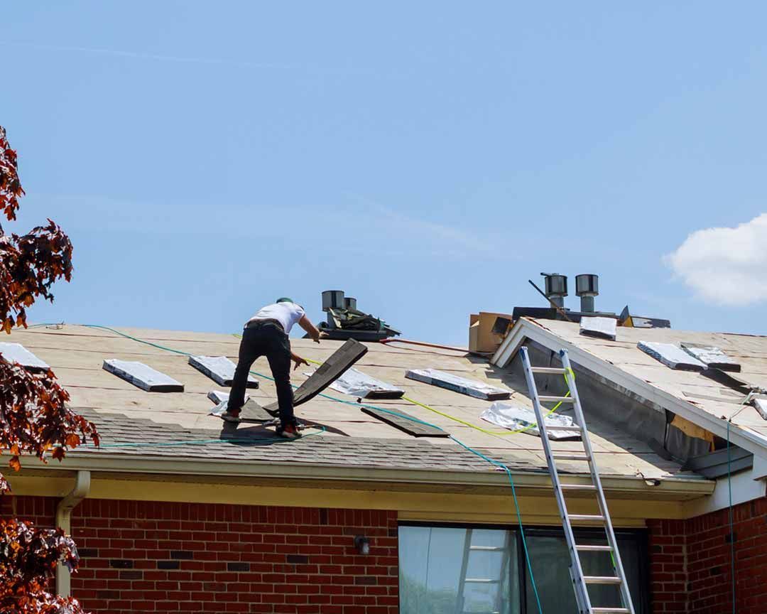 A man is working on the roof of a brick house.