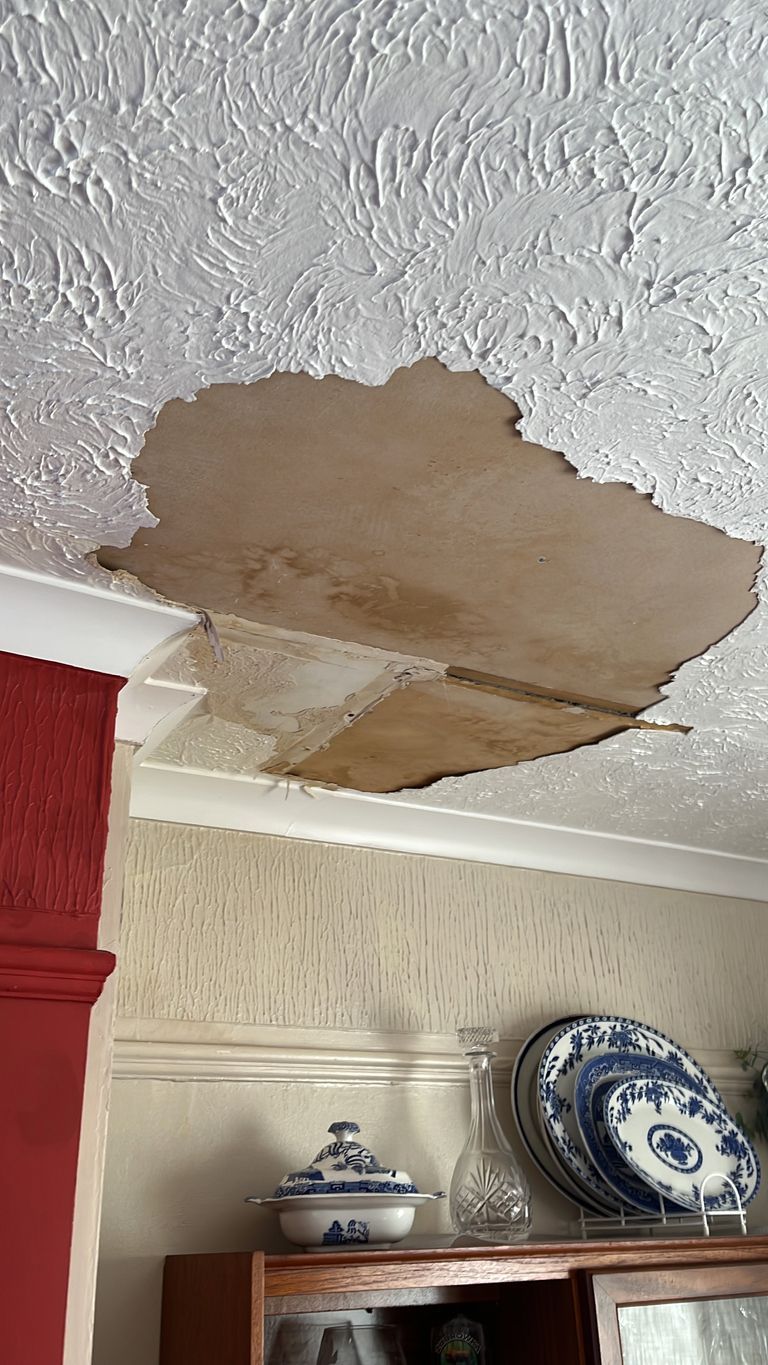 There is a hole in the ceiling in a living room.