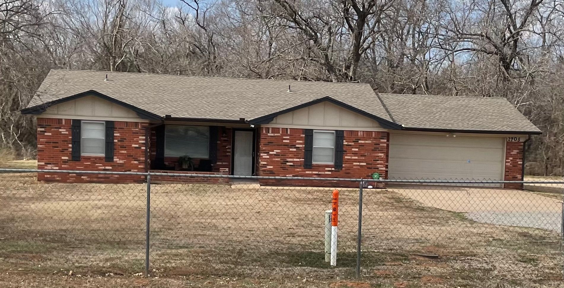 A brick house with a garage and a fence in front of it.