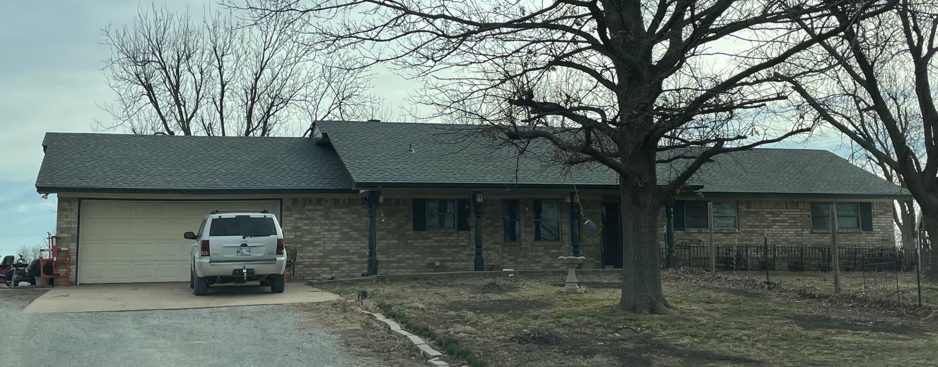 A car is parked in front of a house on a cloudy day.