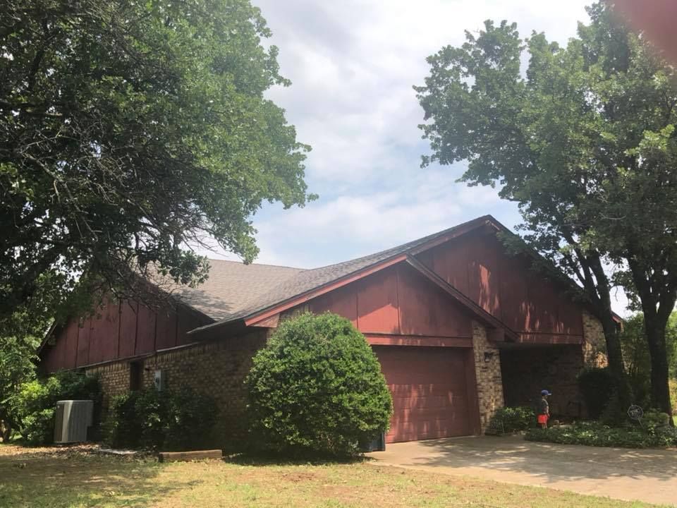 A red house with a garage and trees in front of it