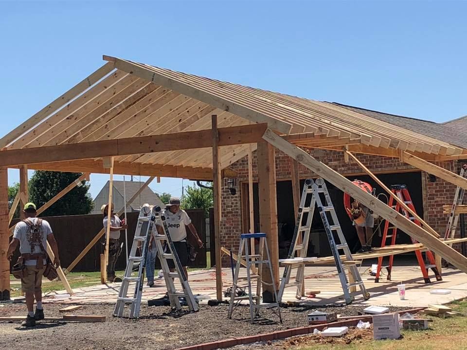 A group of people are working on a wooden structure in front of a house.