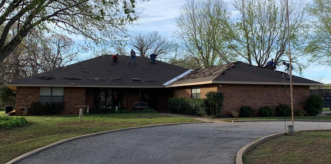 Two men are working on the roof of a brick house.