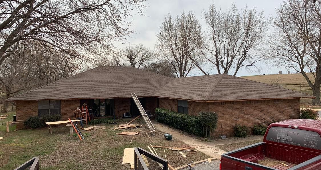 A red truck is parked in front of a house under construction.