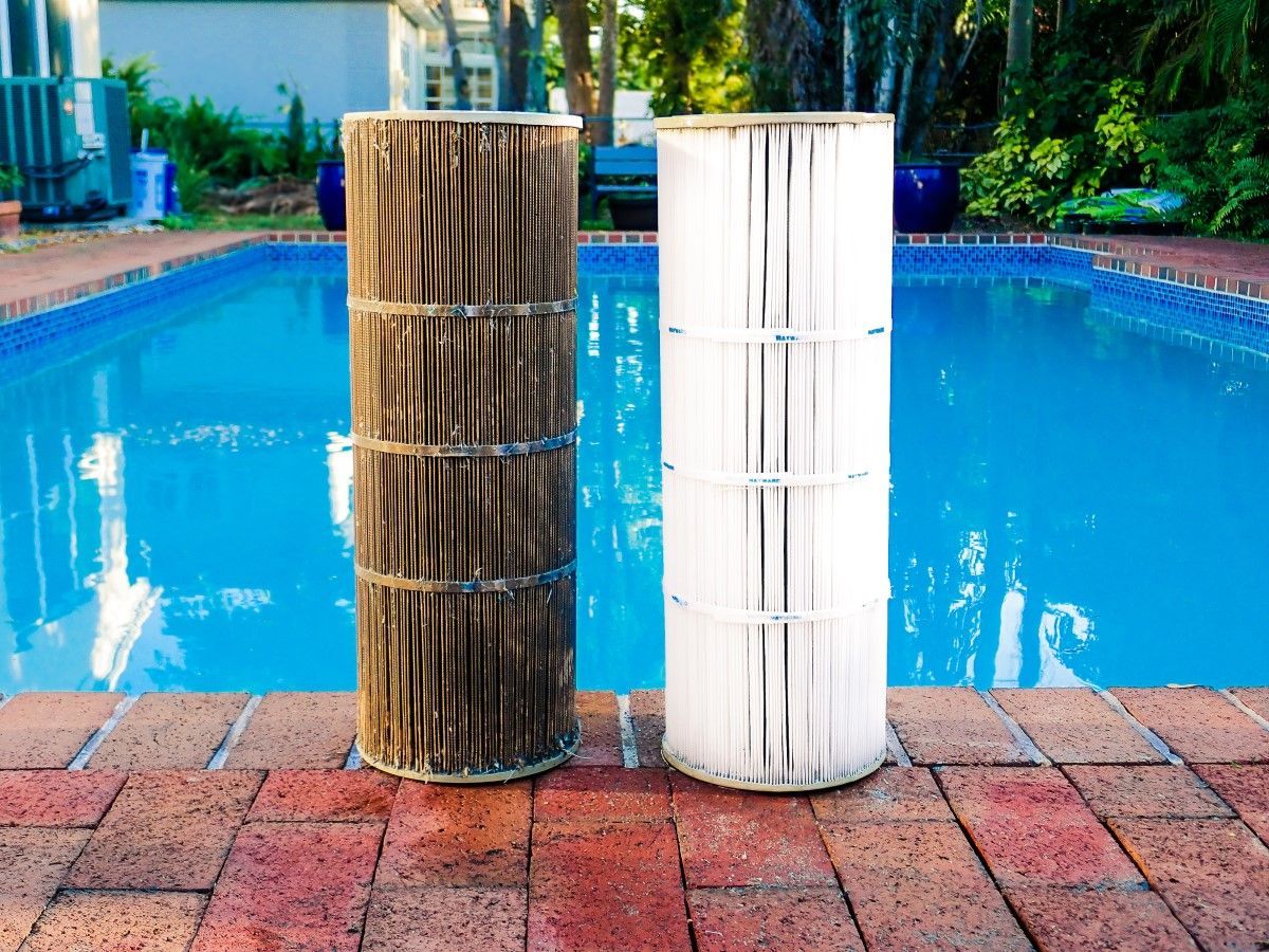 Two pool filters are sitting next to each other on the edge of a swimming pool.