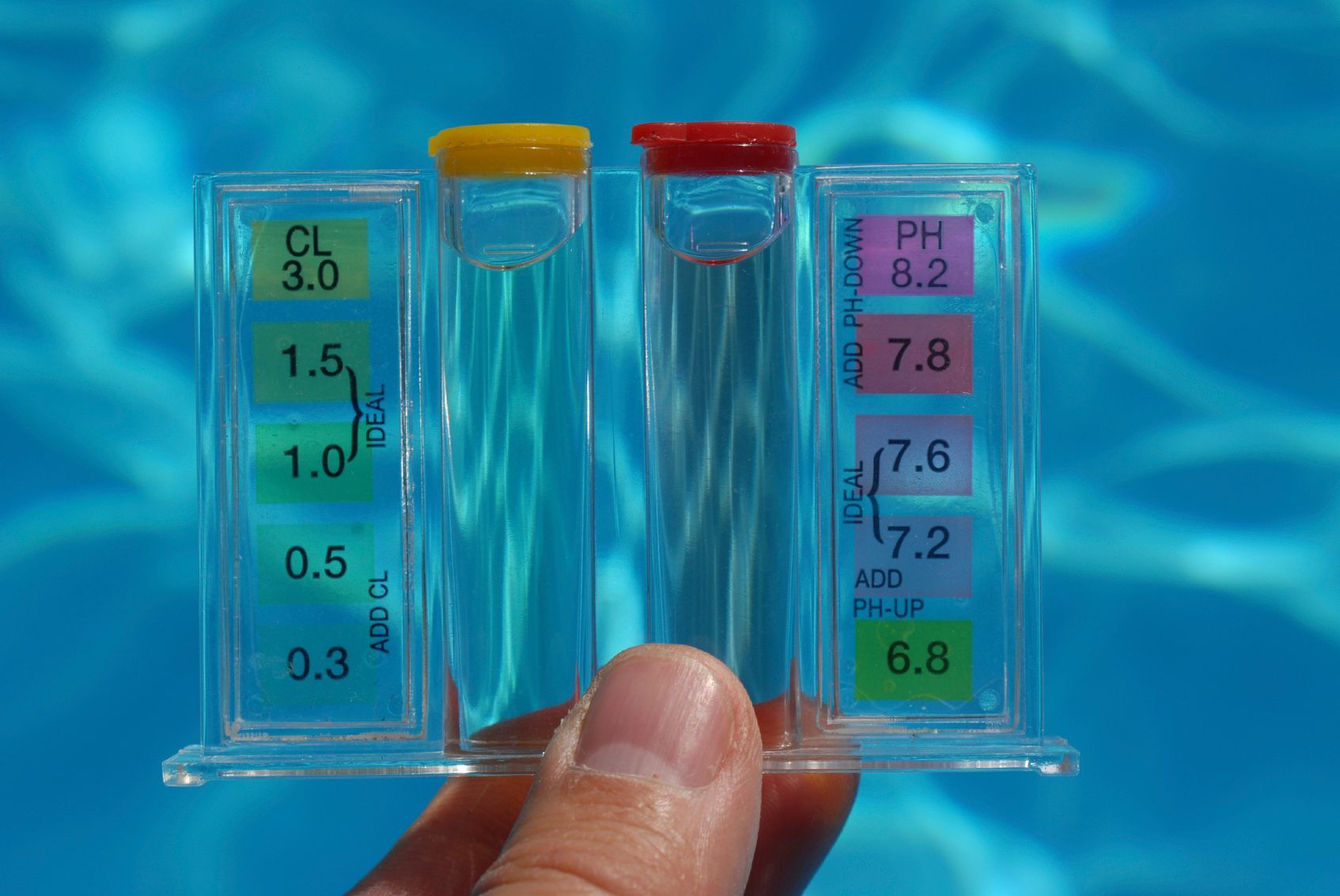 A person is holding a test kit in front of a swimming pool.