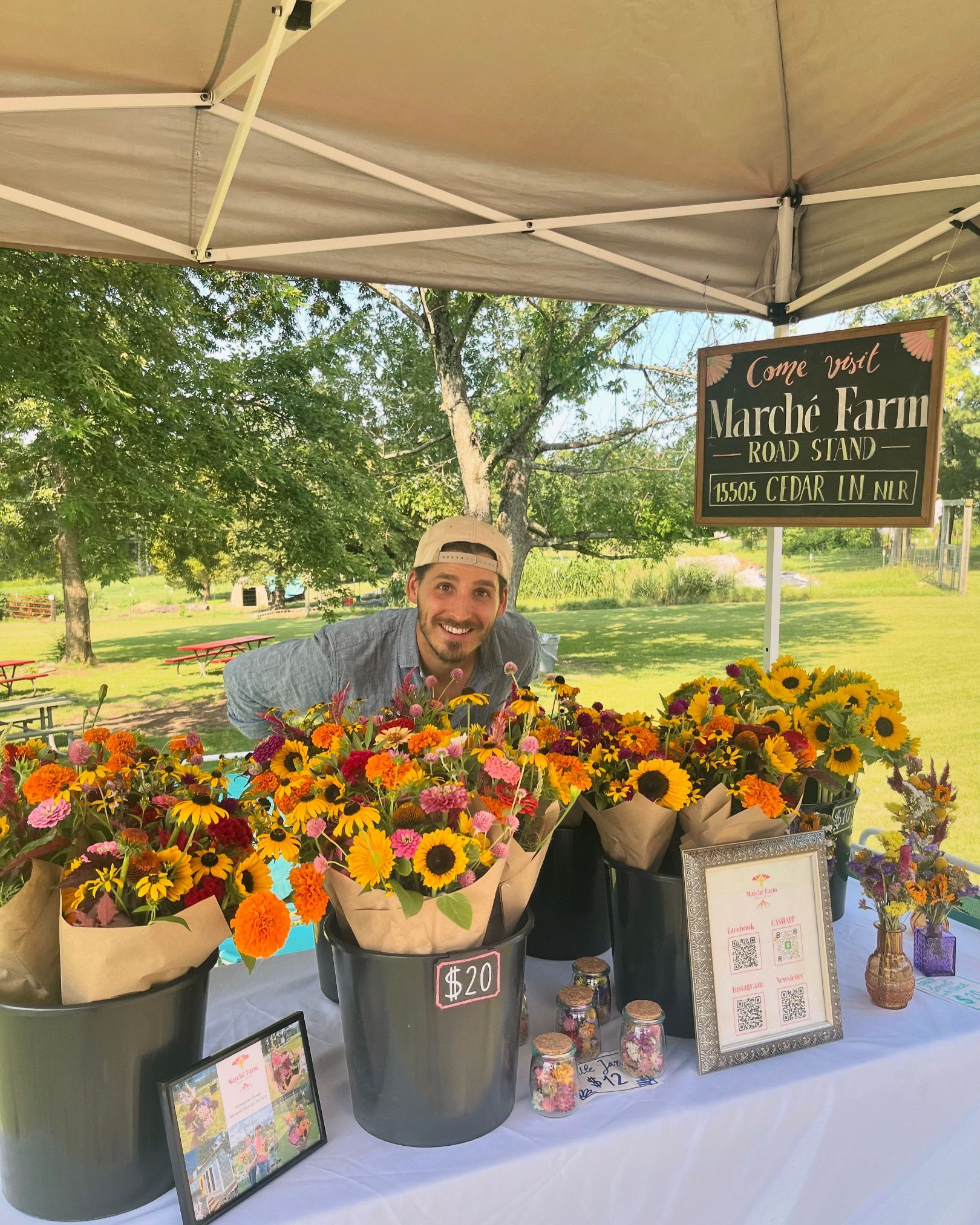 A man is standing in front of a table filled with buckets of flowers.