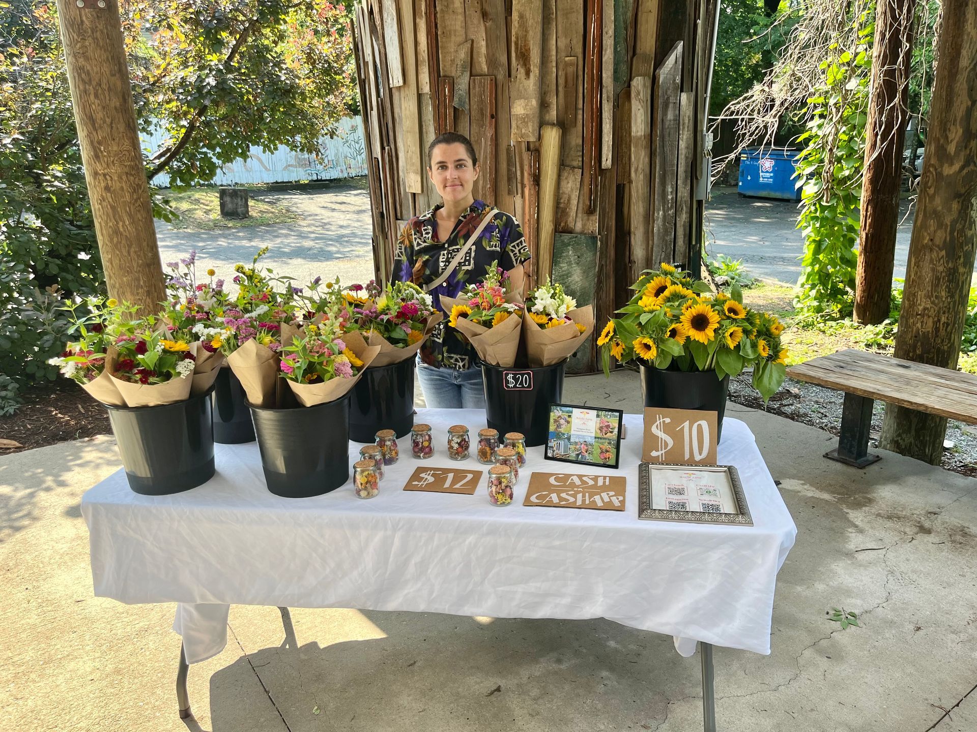 Marine behind their market booth full of fresh flowers at Bernice Garden