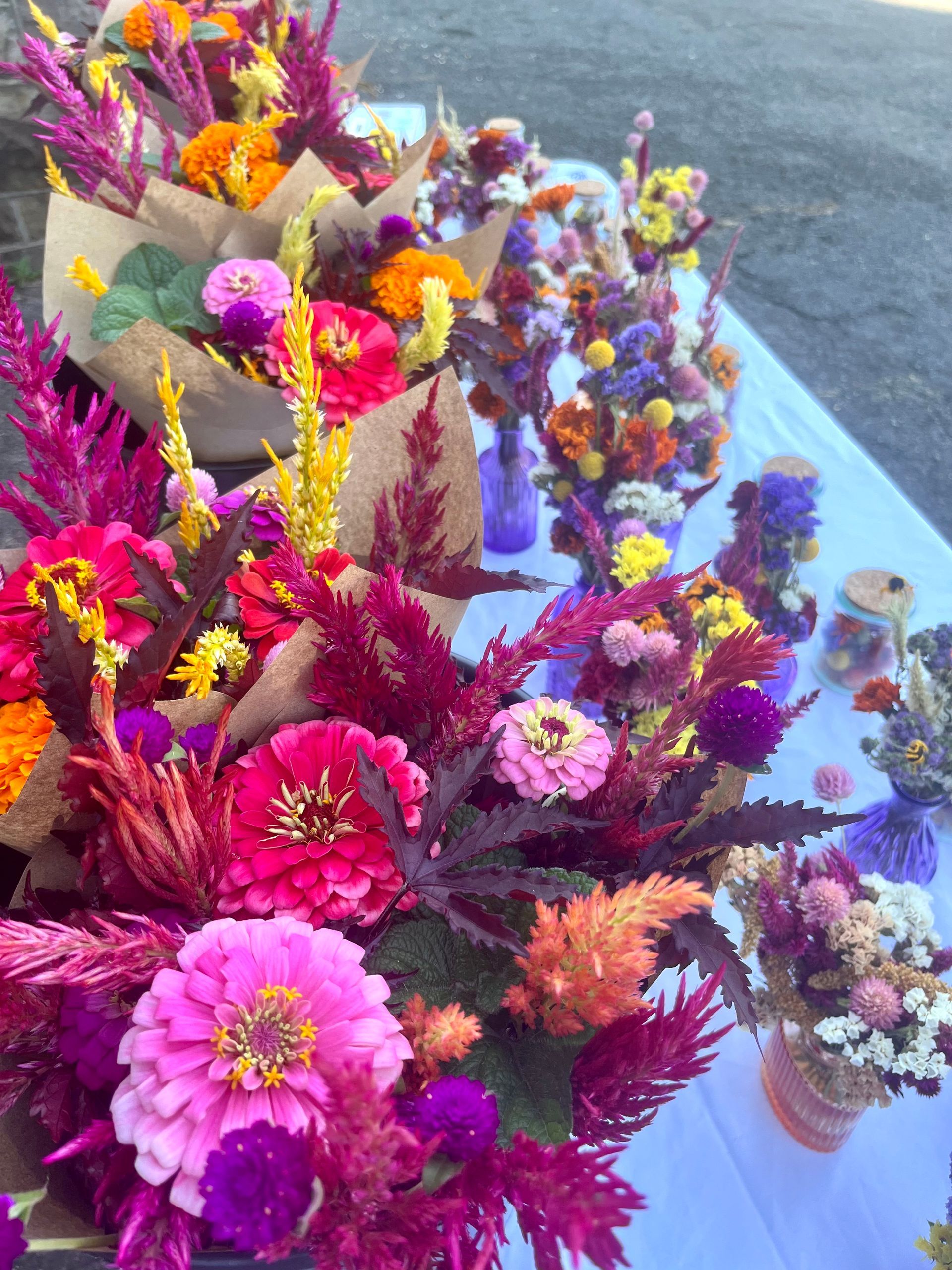 Market booth table full of fresh and dried flowers arrangements