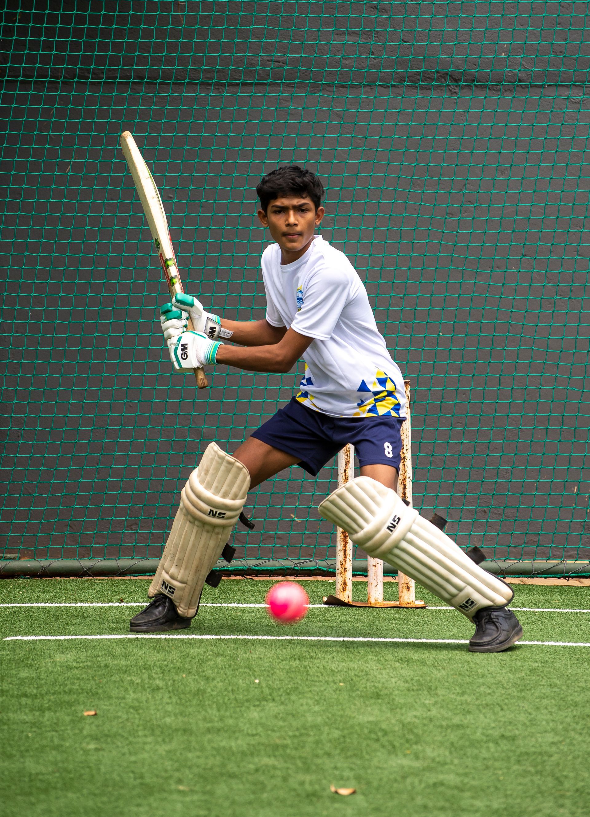 A young boy is playing cricket on a field.