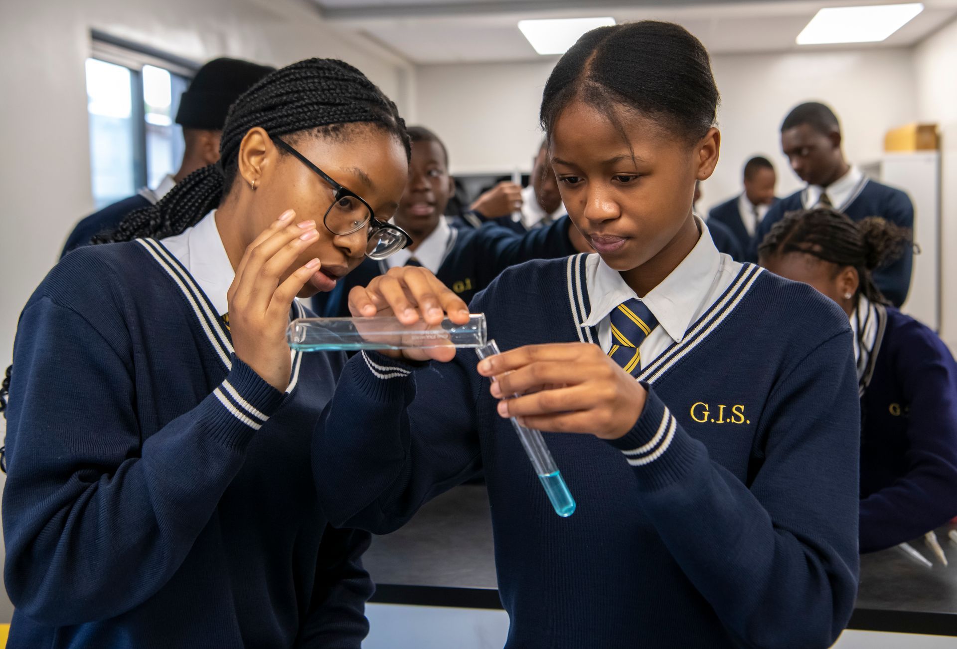 two girls are looking at a test tube in a lab .
