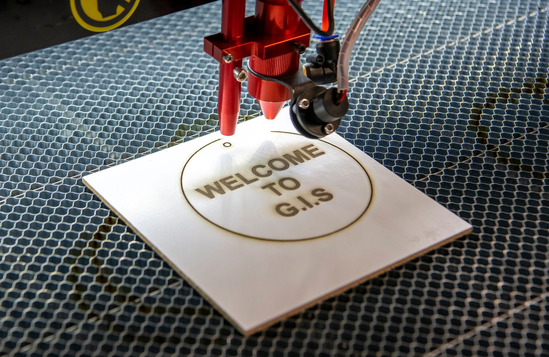 A machine is cutting a piece of paper that says welcome to g.i.s.
