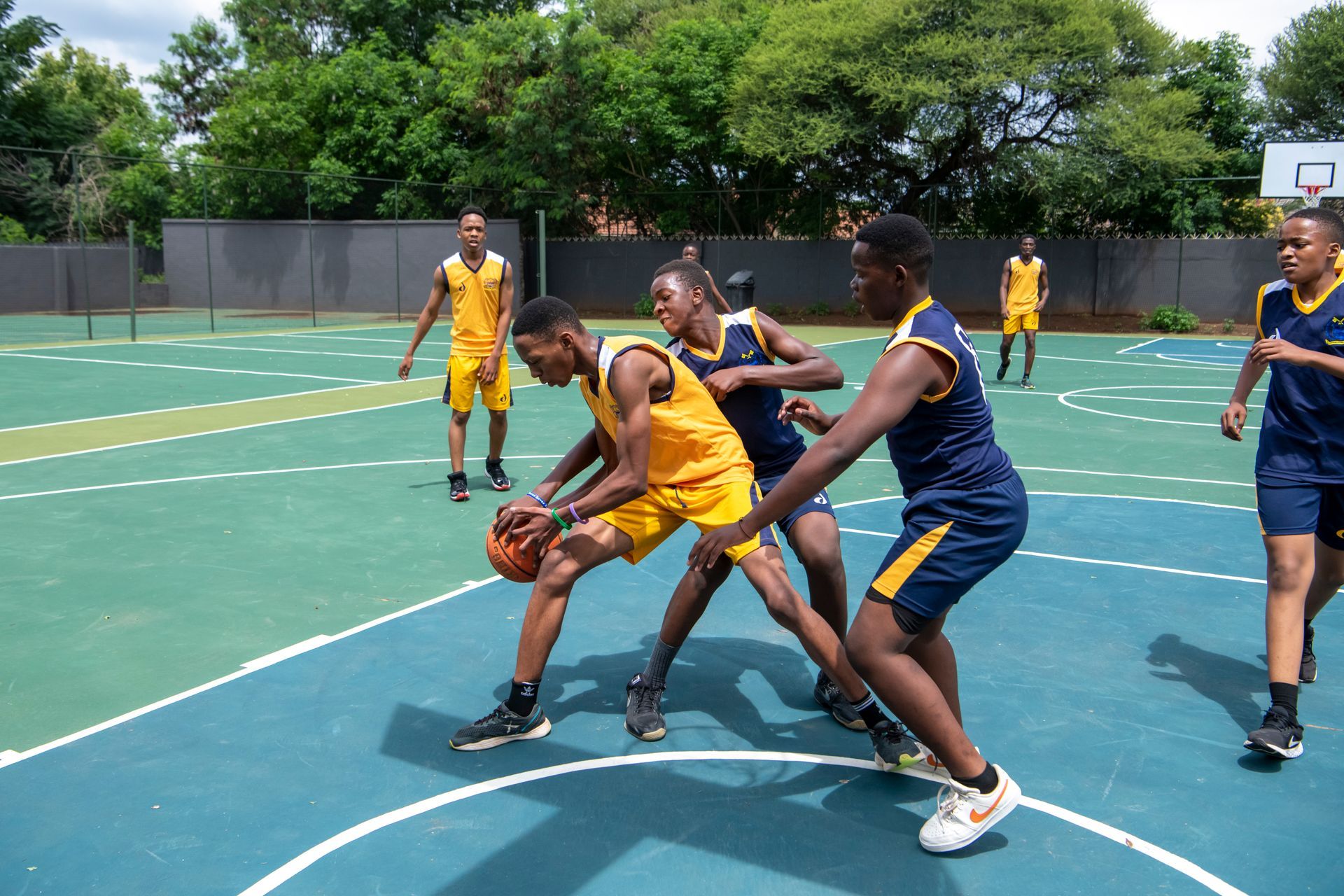 A group of young men are playing basketball on a court.