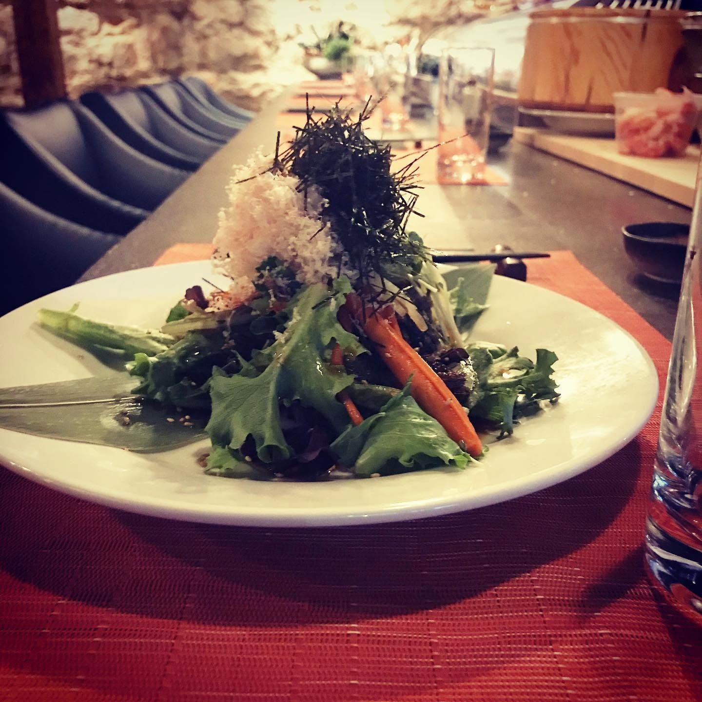 White salad with greens and carrots on a plate at a restaurant table
