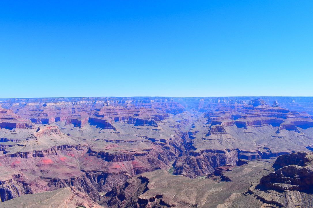 Grand Canyon vista: Layers of red and gray rock formations under a clear blue sky.
