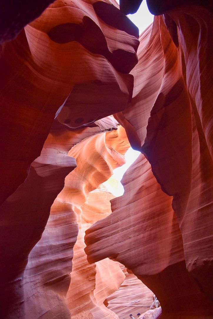 Red and orange sandstone canyon walls with sunlight streaming through the top.