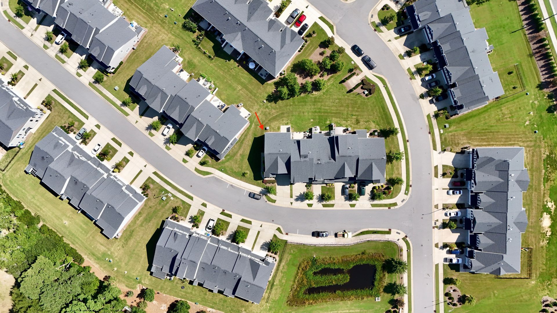 Aerial view of townhouses and roads in a residential neighborhood with green spaces.