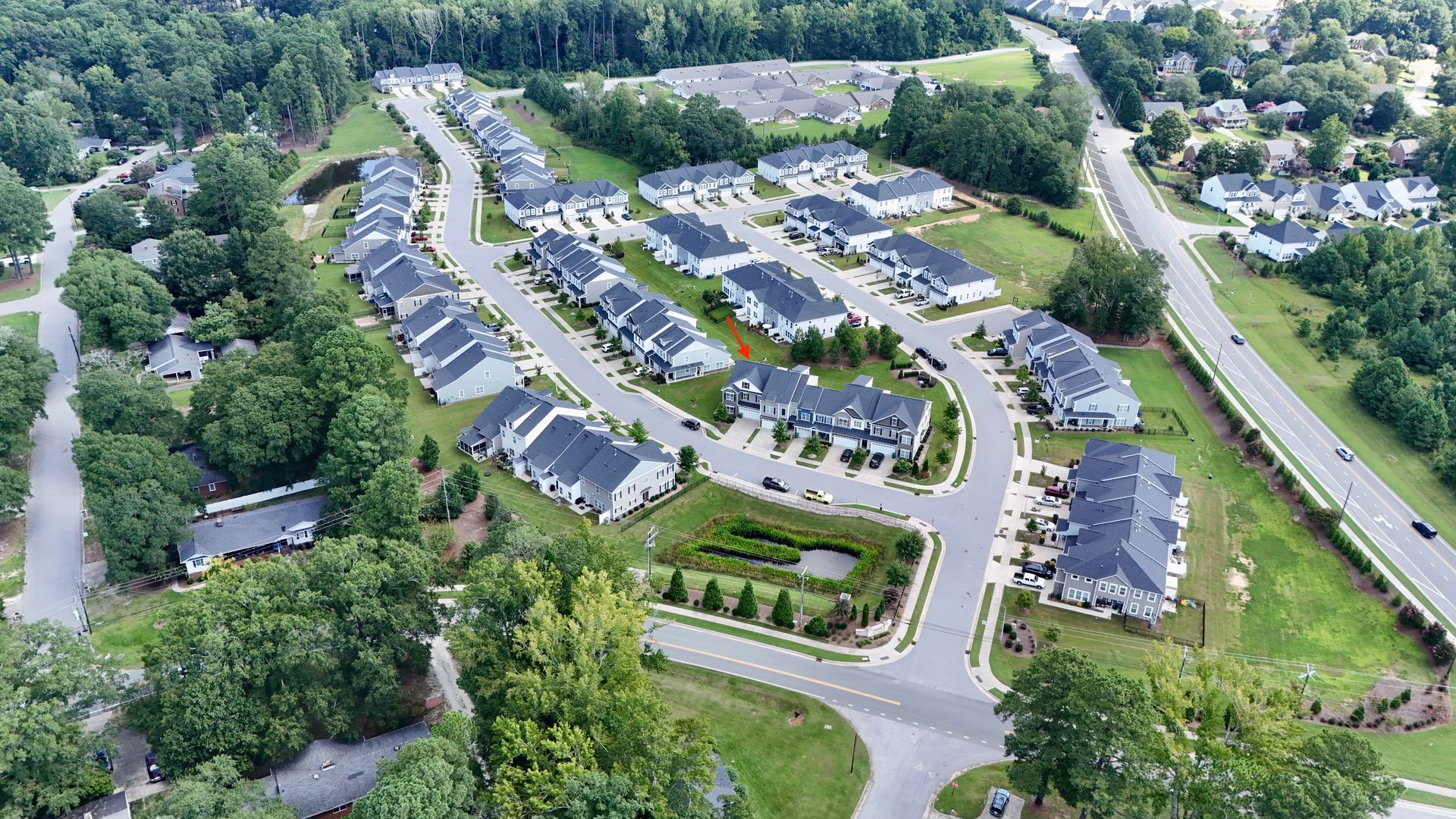 Aerial view of a suburban neighborhood with townhomes, roads, and green space.