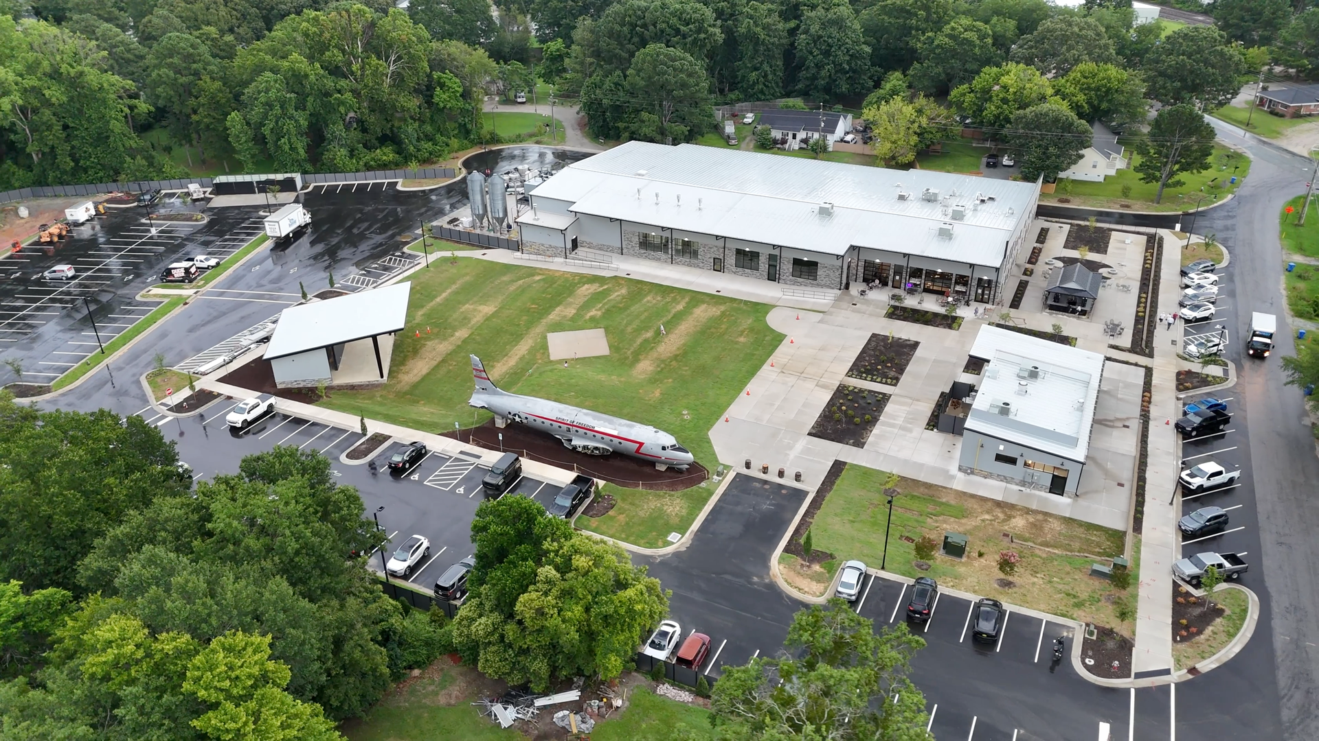 Aerial view of building complex, airplane display, parking, and green space.
