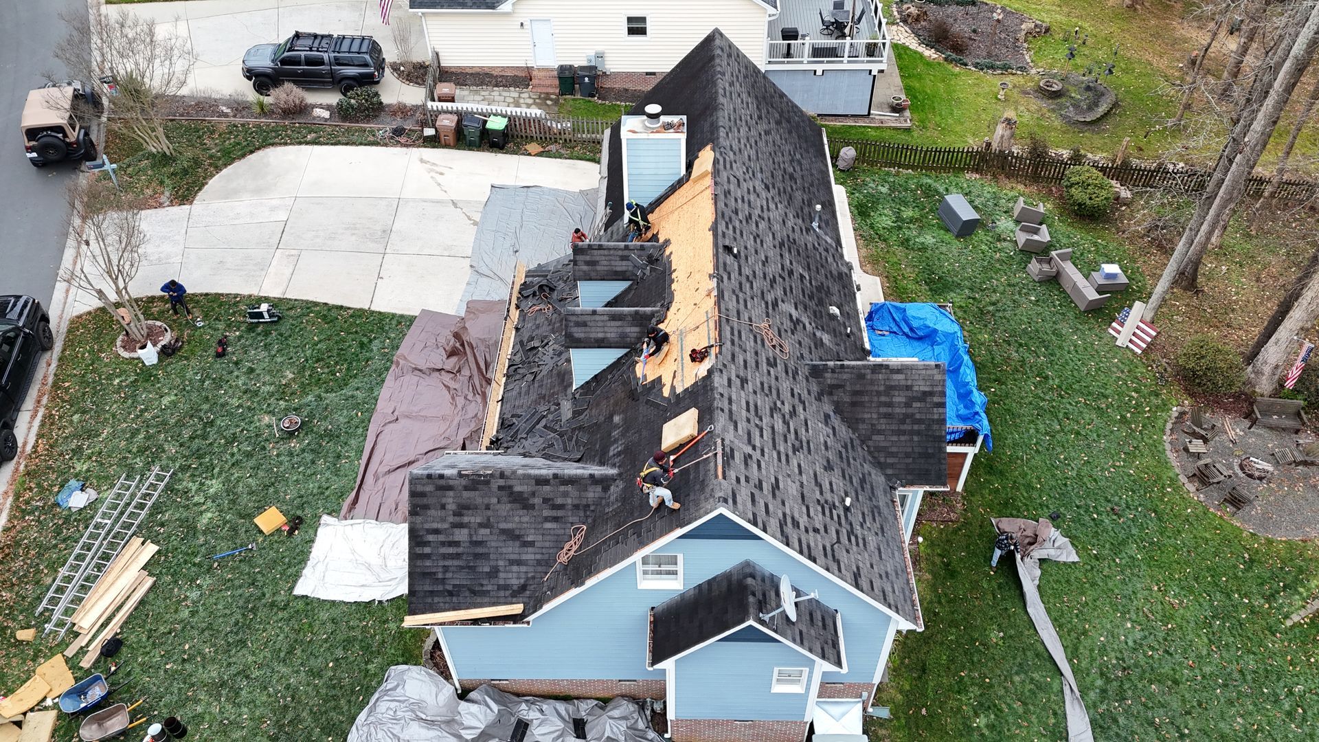 Aerial view of a blue house with significant roof damage after a storm.