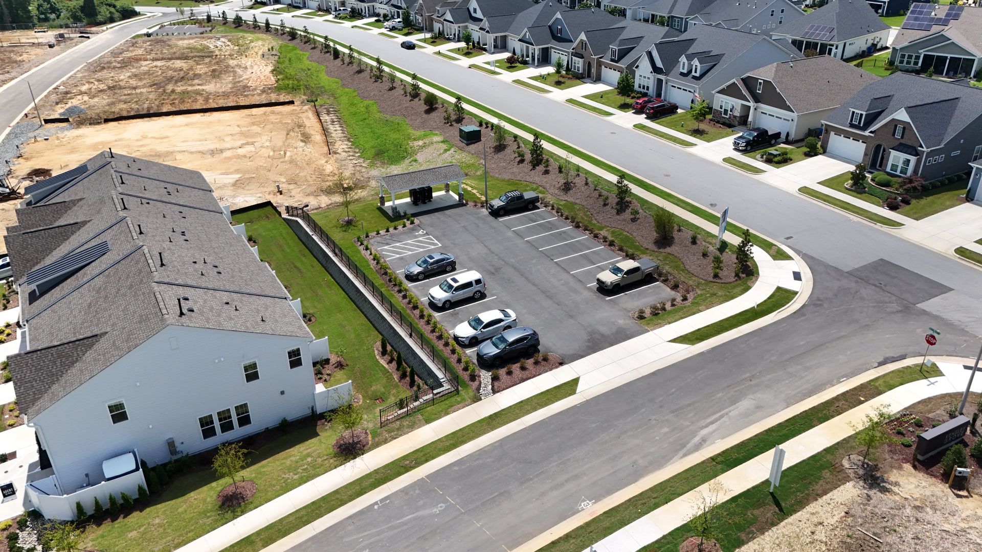 Aerial view of a residential neighborhood with townhouses, parking spaces, and a street.