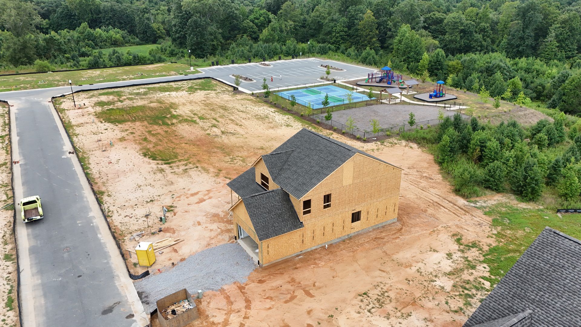 New home construction with a playground and green space in the background.