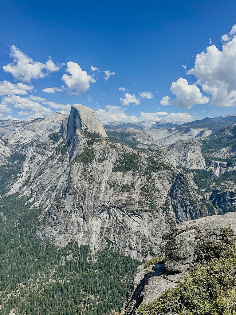 Half Dome at Yosemite National Park, towering granite peak under a blue sky with clouds.
