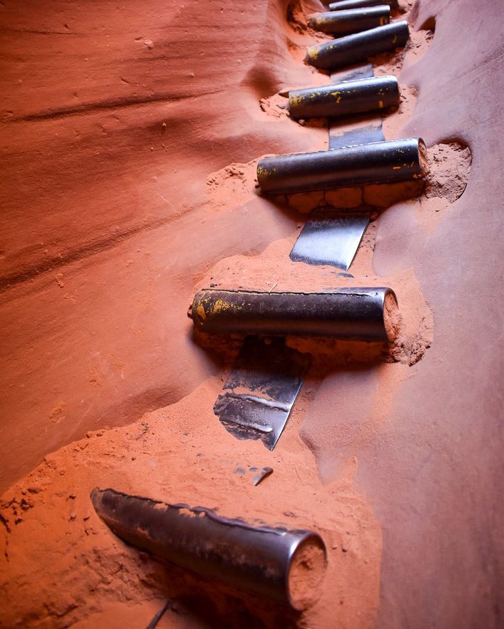 Steps made of metal embedded in the sandy walls of a narrow canyon, for climbing.