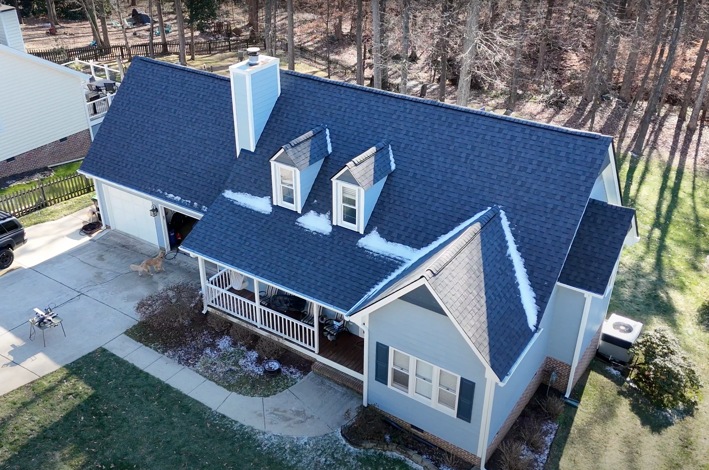 Blue house with dark blue roof, white trim, porch, and two dormers.
