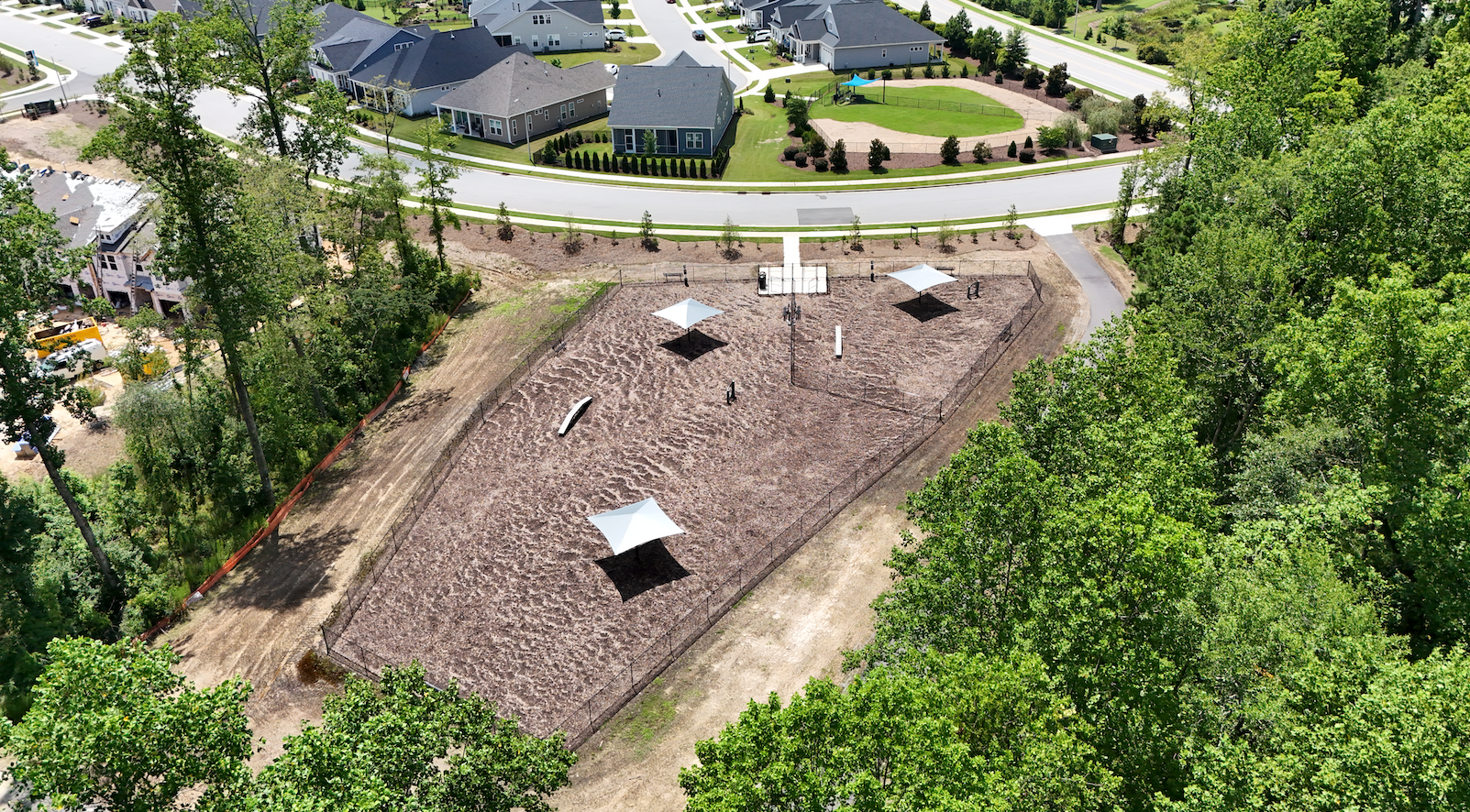 Aerial view of a park with three shade structures, a walking path, and surrounding trees.