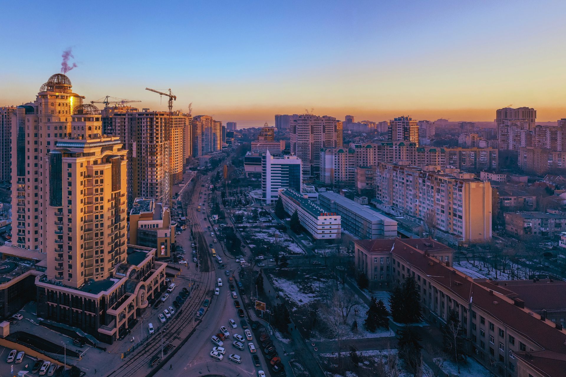 Cityscape at sunset, golden light on buildings. Buildings line a wide avenue.
