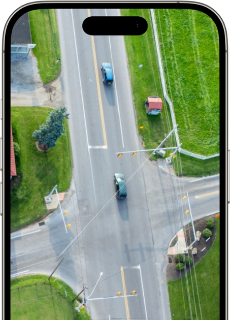 An aerial view of a street intersection with cars driving down it.