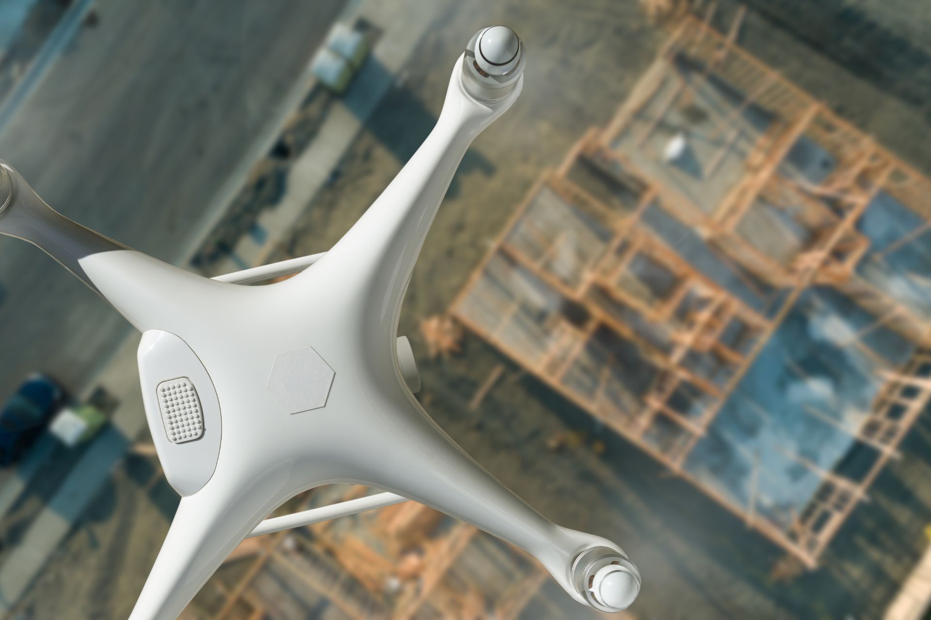 Drone in mid-air, capturing an aerial view of a construction site, showcasing framework and layout.