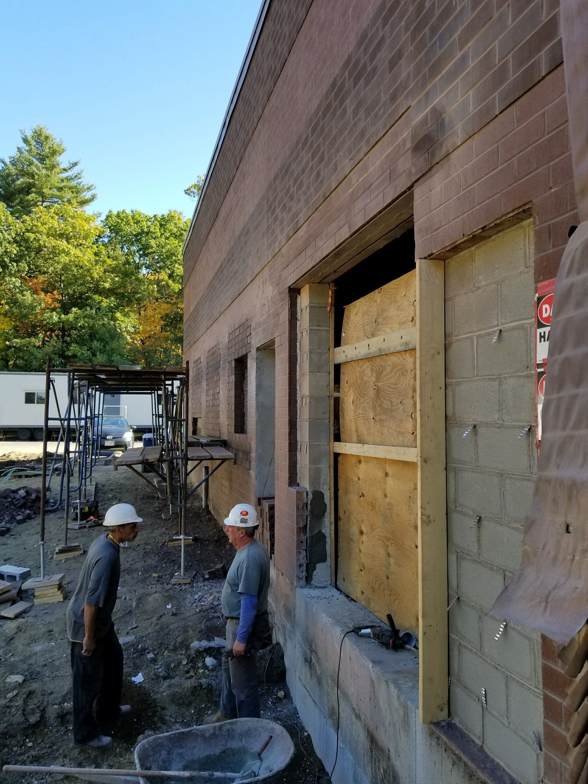 Two construction workers are working on the side of a building