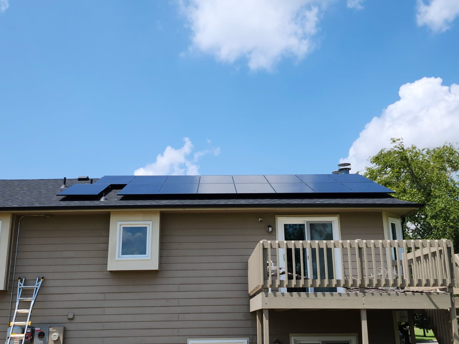 A row of solar panels against a cloudy sky with the sun shining through them.