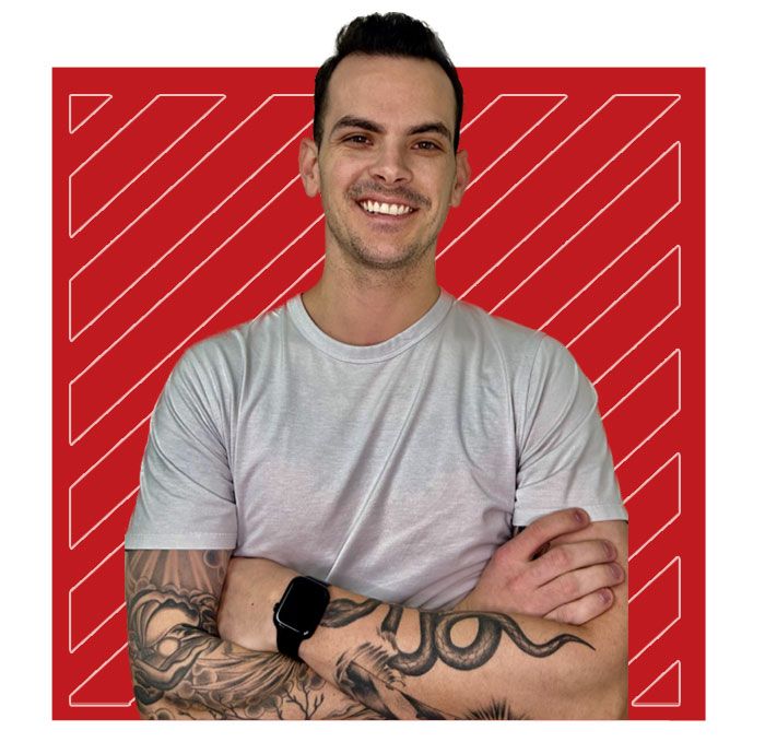 A man with tattoos on his arm is smiling with his arms crossed