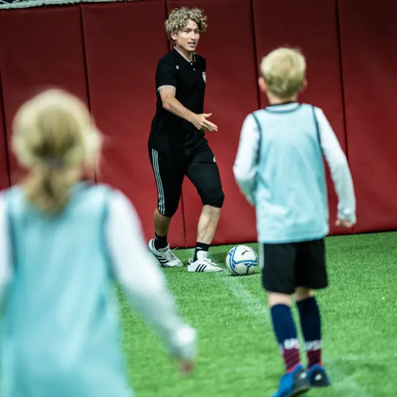 A man and two children are playing soccer on a field