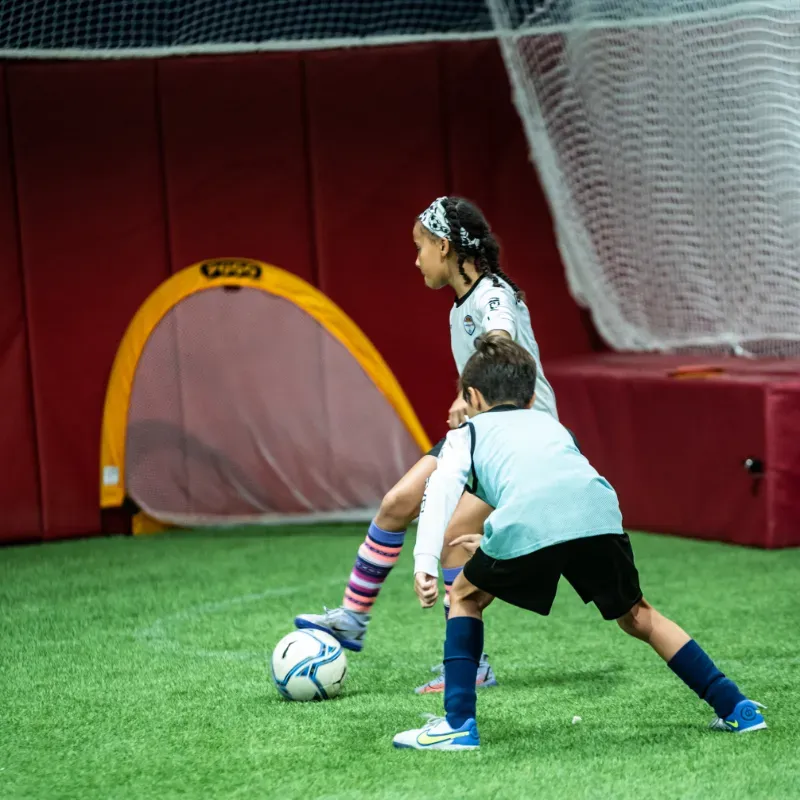 A boy and a girl are playing soccer on a field