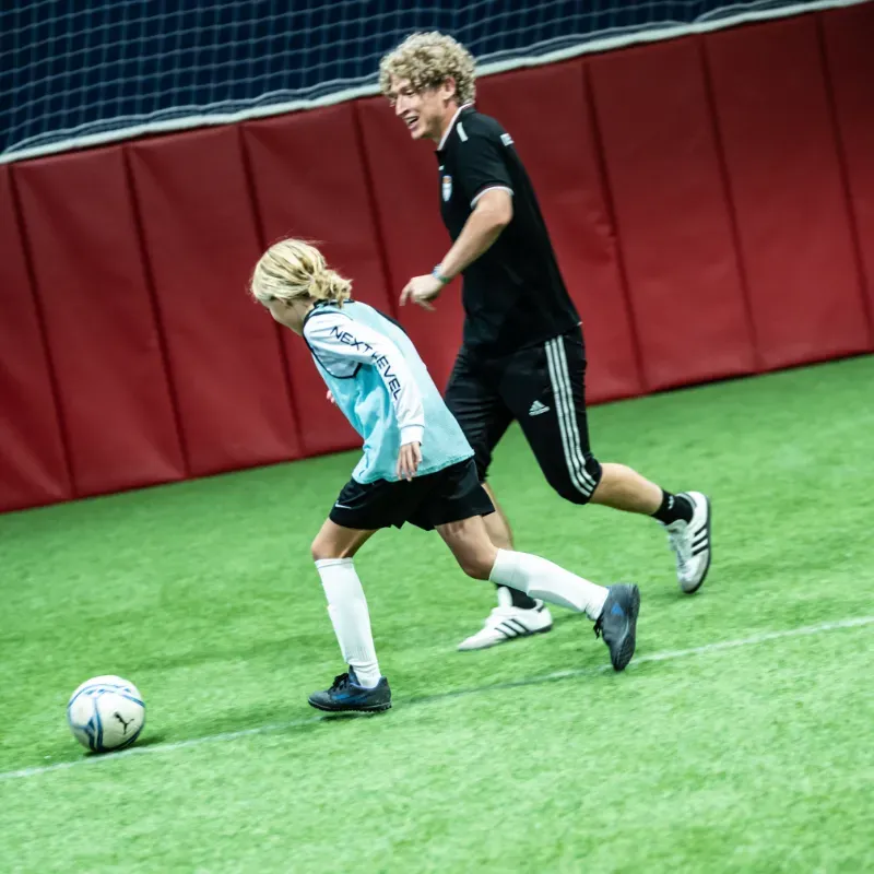 A man and a girl are playing soccer on a field