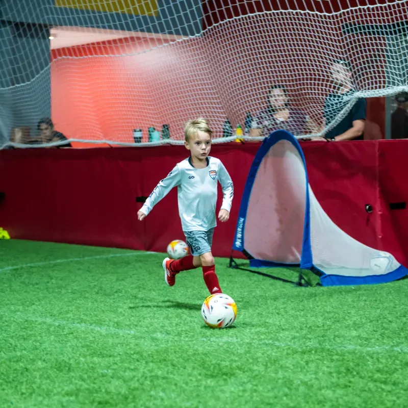 A young boy is kicking a soccer ball on a field.