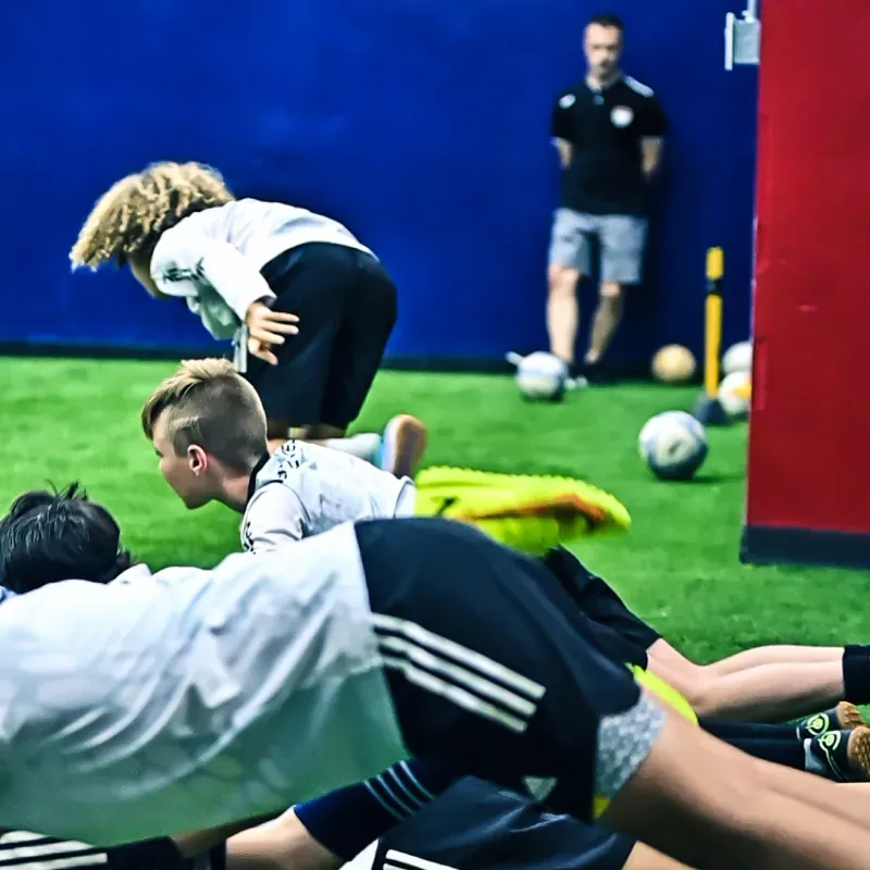 A group of kids are doing push ups in a gym