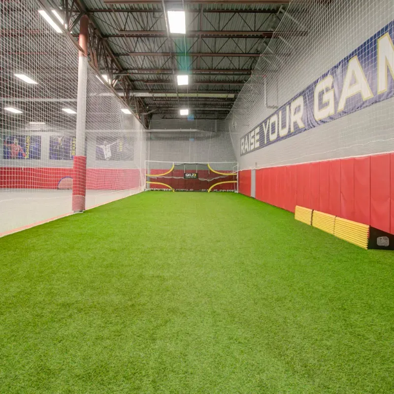 A soccer field with a sign on the wall that says raise your game