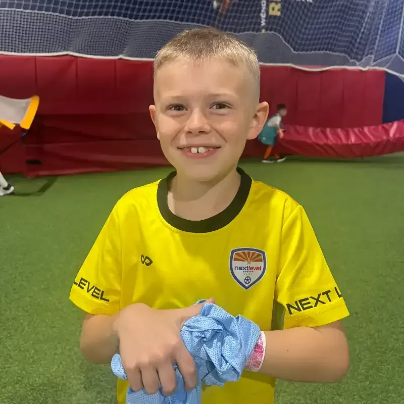 A young boy wearing a yellow shirt that says next level